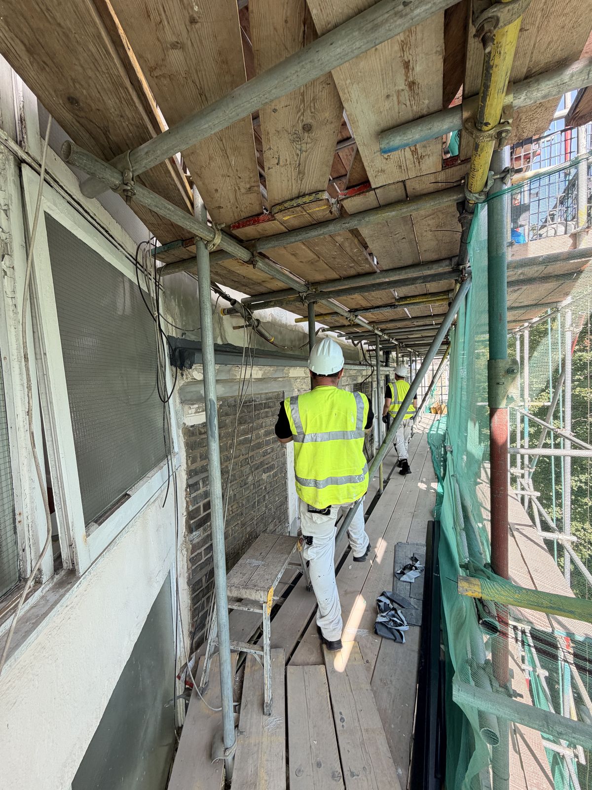 Operatives working from a boarded scaffold lift on the front elevation